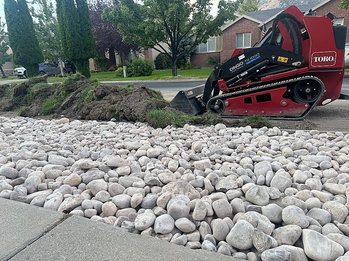 Real landscaping project with mini skid and decorative stone installation